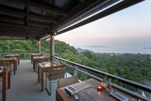 a restaurant with tables and chairs on a balcony at Mantra Samui Resort - Adults Only in Mae Nam