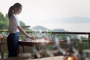 a woman standing at a table with wine glasses at Mantra Samui Resort - Adults Only in Mae Nam