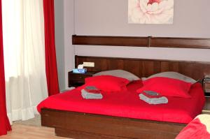 a bedroom with a red bed with red pillows at Hotel Restaurant Le Paris in Mondorf-les-Bains