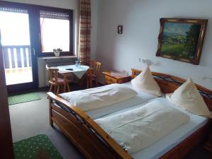 - une chambre avec un grand lit et une table avec des chaises dans l'établissement Pension Mühlencafé, à Breitnau