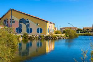 a building on the side of a river at Goélia Le Village Club Marin in Port-la-Nouvelle