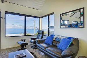 a living room with a leather couch and chairs at Park Beach Retreat in Dodges Ferry