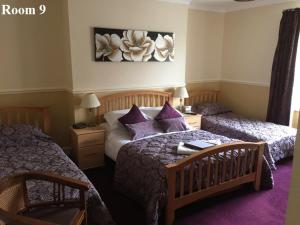Un dormitorio con dos camas con almohadas moradas. en The Arches Guest House, en Whitby
