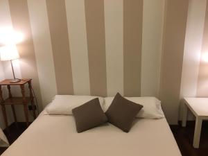 Una cama con dos almohadas encima en una habitación. en IN PIAZZA appartamento con vista, en Lazise