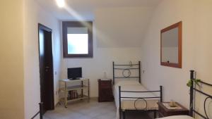 a bedroom with a bed and a desk with a television at Affittacamere Peonia in Oliena