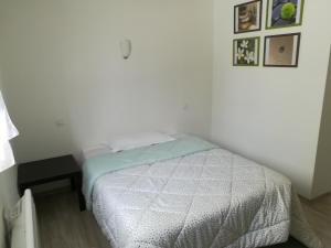 ein weißes Schlafzimmer mit einem Bett und einem Tisch in der Unterkunft Appartement au calme in Saint-Maurice-de-Gourdans