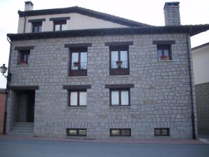 un edificio de piedra con ventanas y macetas. en Casa Alval, en Villacastín