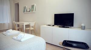 Cette chambre blanche dispose d'une télévision, d'un lit et d'une table. dans l'établissement Little Suite - Stella, à Lille
