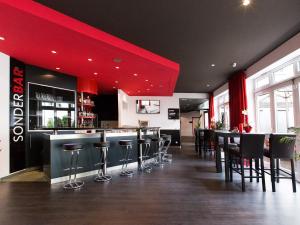 um restaurante com bancos de bar e um tecto vermelho em DORMERO Hotel Dresden Airport em Dresden
