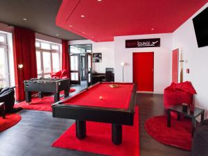 a living room with a pool table and red carpet at DORMERO Hotel Dresden Airport in Dresden