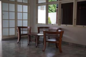 a dining room with a table and chairs and windows at Cozy Home in Denpasar