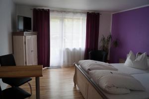 1 dormitorio con 2 camas y pared púrpura en Gästehaus zur Mühle Dehm, en Friedrichshafen