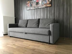 a couch sitting in a living room with a wooden floor at Les Appartements Paris Clichy in Clichy