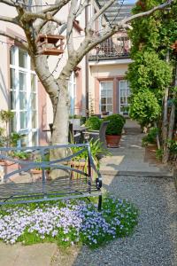 um banco sentado em frente a uma árvore com flores em Hotel garni Kaiserstuhl em Ihringen