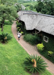 une femme s'engageant sur un chemin en face d'un bâtiment au toit de chaume dans l'établissement Hippo Hollow Country Estate, à Hazyview