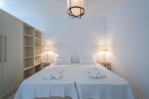 a white bedroom with two beds and two lamps at THOAS Residences in Moúdhros