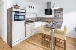 a kitchen with white cabinets and a table with chairs at Gartenpalais 2 in Norderney +8 photos