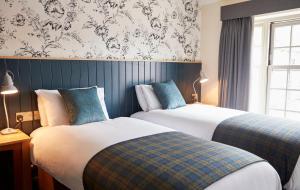 two beds sitting next to each other in a bedroom at Swan Hotel by Greene King Inns in Thaxted