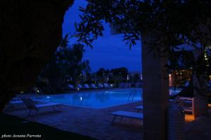 una piscina por la noche con dos bancos alrededor en Masseria Torre Del Diamante, en Torre Canne