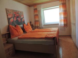 シュトローブルにあるFerienwohnung Matthias Unterbergerのベッドルーム1室(オレンジ色の枕と窓付)