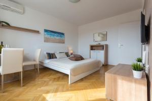 a white bedroom with a bed and a table at Luma Studio in Dubrovnik
