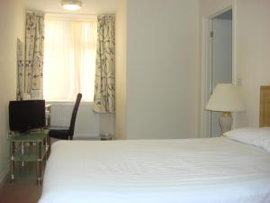a bedroom with a white bed and a desk and a window at Carrington House Hotel in Bournemouth
