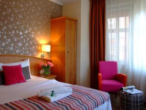 a bedroom with a bed and a pink chair at Hotel Stare Miasto Old Town in Poznań +222 photos
