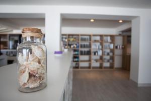 a glass bottle filled with sand and seashells on a counter at Hotel Rosamar - Emar Hotels in Es Pujols