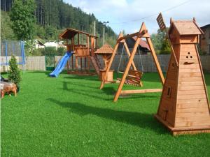 a playground with wooden play equipment on the grass at Penzión Centrál in Oščadnica
