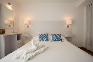 a white bed with towels on it with two blue pillows at Hotel Rosamar - Emar Hotels in Es Pujols
