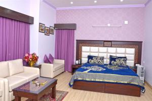 een slaapkamer met een bed, een bank en een tafel bij Hotel Shikhar & Restaurant in Almora