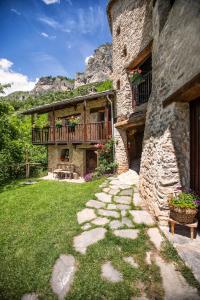 een stenen huis met een balkon en een tuin bij Locanda del Silenzio Hotel in Macra