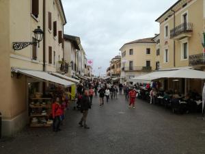 a crowd of people walking down a street with buildings at Bardolino Via Marconi in Bardolino