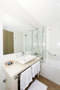 uma casa de banho branca com um lavatório e um chuveiro em Hotel Marul em Split