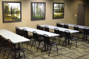 ein Zimmer mit Tischen, Stühlen und Gemälden an der Wand in der Unterkunft Heartland Inn Hotel and Suites in Park Rapids