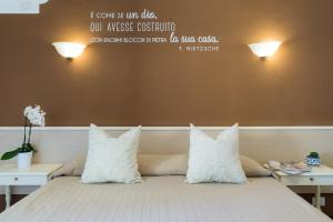ein Bett mit weißen Kissen und Worten an der Wand in der Unterkunft Hotel Villa Rita in Paestum