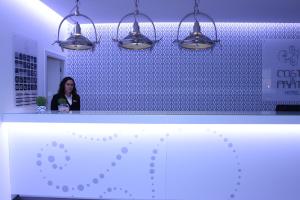 a woman standing in front of a blue wall with lights at Costa de Prata Hotel in Figueira da Foz