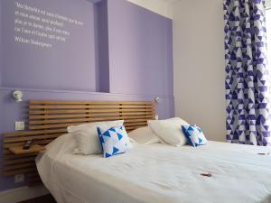 ein Schlafzimmer mit einem Bett mit zwei blauen und weißen Kissen in der Unterkunft Villa TerraMera Hôtel in Le Lavandou