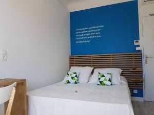 ein Bett mit zwei Kissen und einer blauen Wand in der Unterkunft Villa TerraMera Hôtel in Le Lavandou