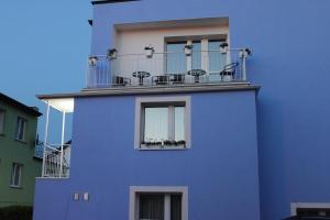 un edificio azul con un balcón con sillas. en Bosmanska 11, en Darłówko