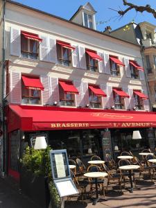 un restaurant avec des tables et des chaises en face d'un bâtiment dans l'établissement Hotel l'Avenue, à Chantilly