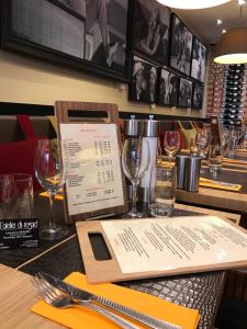 a table in a restaurant with a menu and wine glasses at Hotel l'Avenue in Chantilly