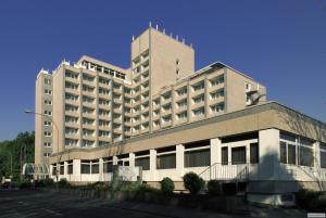 a large white building with a parking lot in front of it at H4 Hotel Frankfurt Messe in Frankfurt