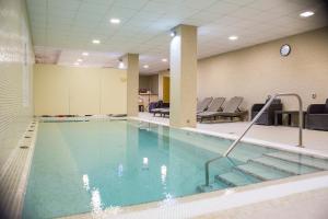 a swimming pool with chairs and a clock on the wall at Hotel Szent István in Eger