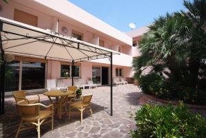a patio with a table and chairs and an umbrella at Hotel Barcarola 2 in Marina di Campo