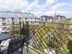 a balcony with two chairs and a table and some buildings at VacationClub - Regina Maris Apartment 71 in Świnoujście