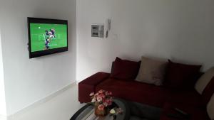 un soggiorno con divano rosso e TV a schermo piatto di Residence Cheikh Fall a Dakar