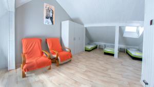 Pokój na poddaszu z 2 pomarańczowymi krzesłami i łóżkami piętrowymi w obiekcie Place4Us w Warszawie