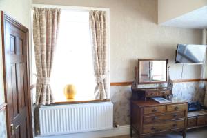 a living room with a tv and a dresser at Keswick Park Hotel in Keswick