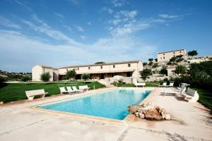 a swimming pool with chairs and a building at Valle dell'Acanto in Modica